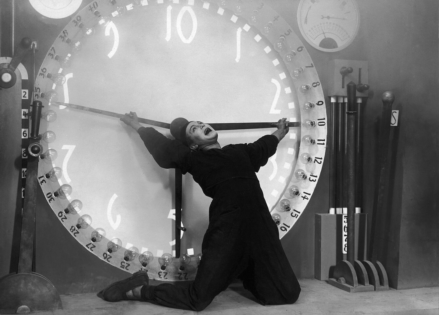 Gustav Fröhlich hängt an den Zeigern einer Uhr