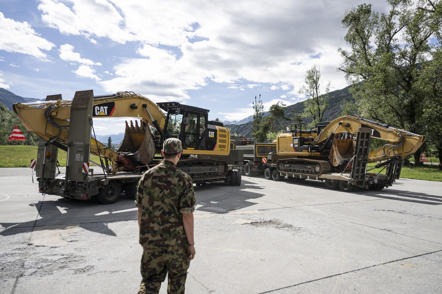 Helfer können verschüttetes Dorf nicht betreten Ein Soldat vor Baggern auf Tiefladern