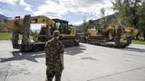 Ein Soldat vor Baggern auf Tiefladern