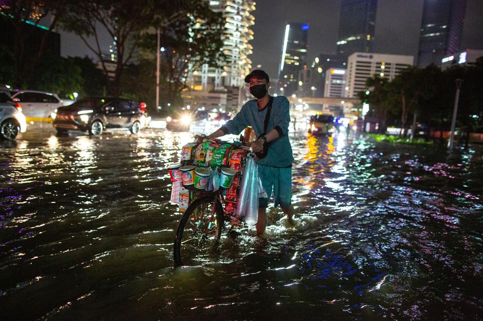 Straßenhändler im überschwemmten Jakarta: Wer zu den Auswirkungen des Klimawandels forscht, erlebt das oft selbst als psychisch belastend 1.4993