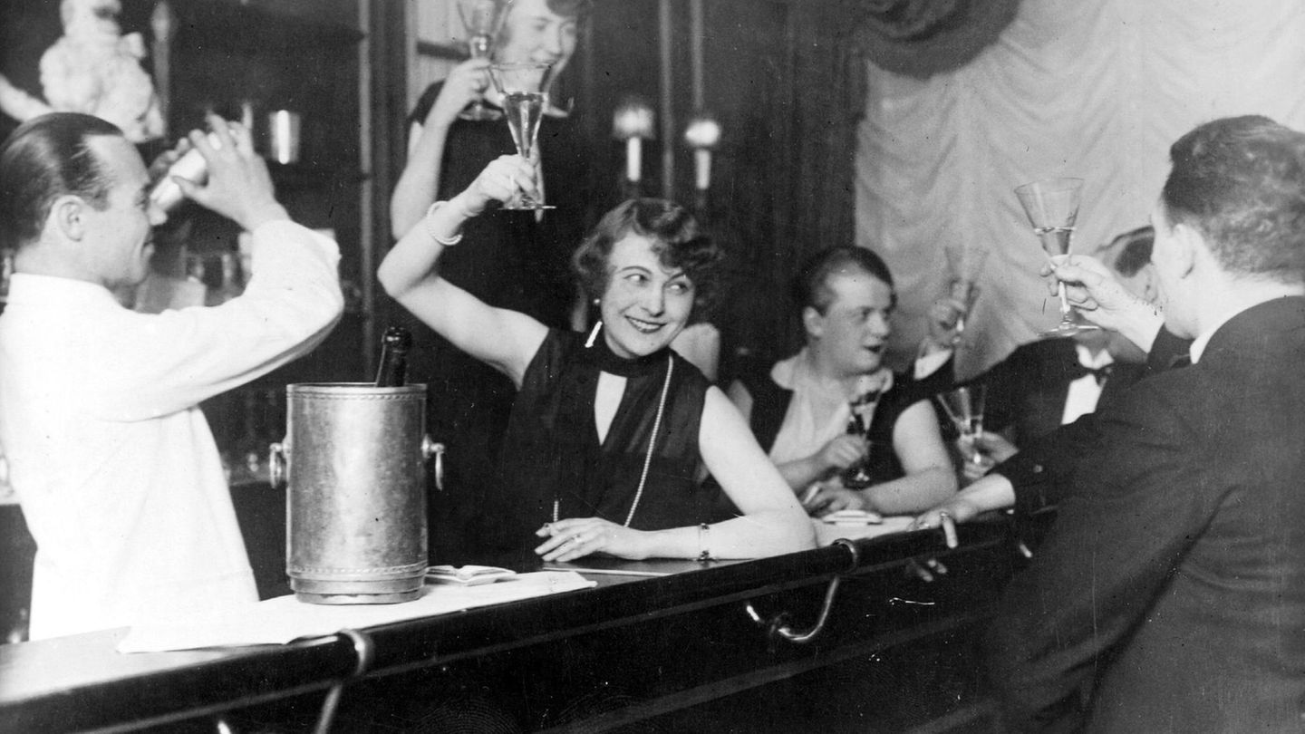 Die Welt auf Drogen Gäste an der Theke einer Bar stoßen mit Sekt an.