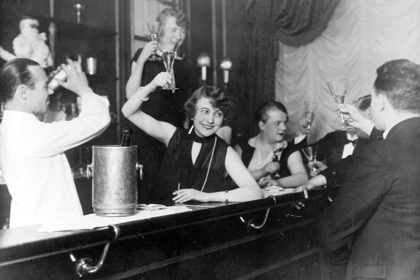 Die Welt auf Drogen Gäste an der Theke einer Bar stoßen mit Sekt an.