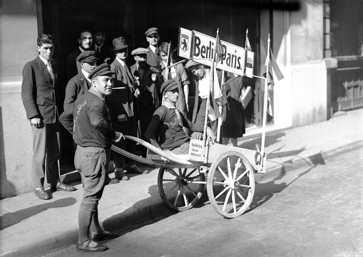 Personen schieben eine Schubkarre, in der jemand sitzt