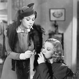 Eine Frau zündet einer anderen Frau eine Zigarette mit einem Streichholz an