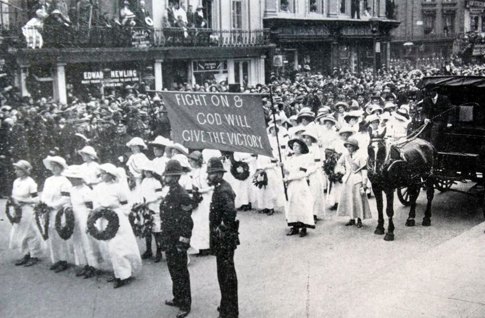 Schwarz-Weiß-Foto eines Trauermarsches durch London: in weiß gekleidete Frauen ziehen an Zuschauern entlang