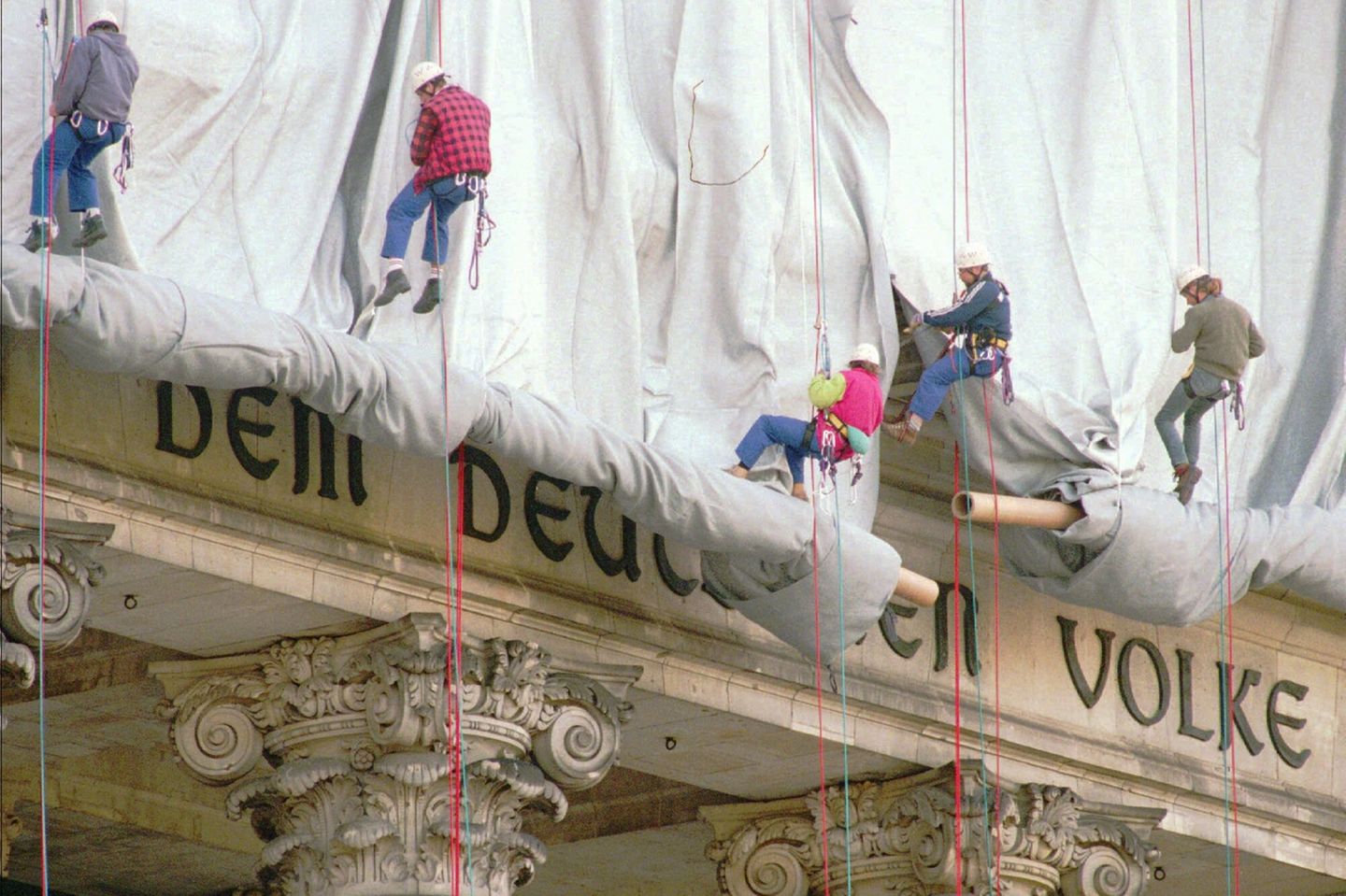 Gewerbekletterer seilen sich vom Reichstagsgebäude ab, um Stoffbahnen abzurollen. Dahinter der Schriftzug: dem deutschen Volke