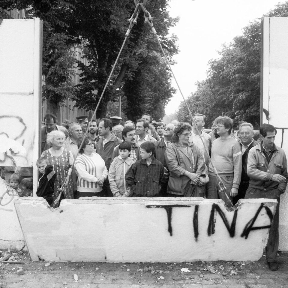 Zum Abheben: Nach Jahrzehnten der Teilung bricht ein Bagger ein Stück aus der Berliner Mauer an der Bernauer Straße. Um einen Blick auf die andere Seite zu werfen, sind Hunderte Neugierige gekommen
