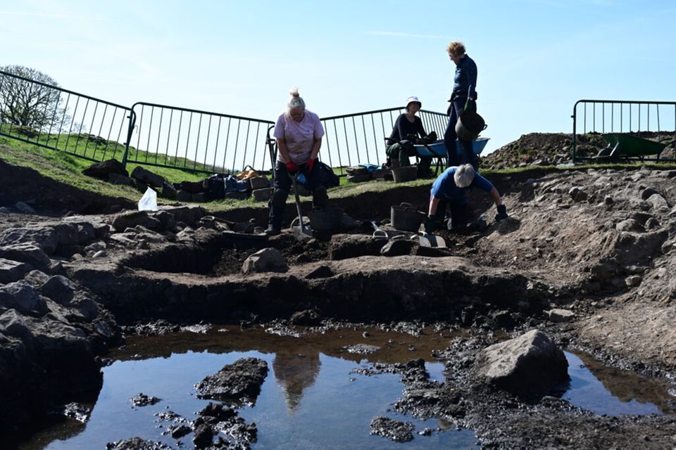 Frauen und Männer bei Ausgrabungen, in der Fläche steht Wasser