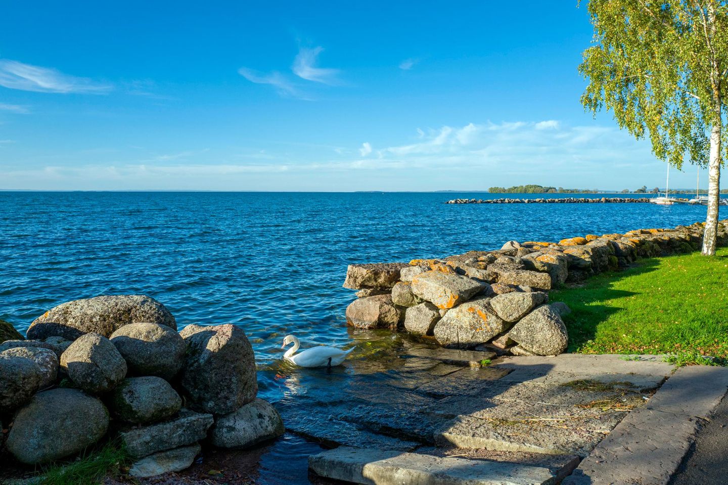 Idylle am Wasser: Schwedens Land der Tausend Seen See Vättern, im Vordergrund Steinmauern und ein Schwan