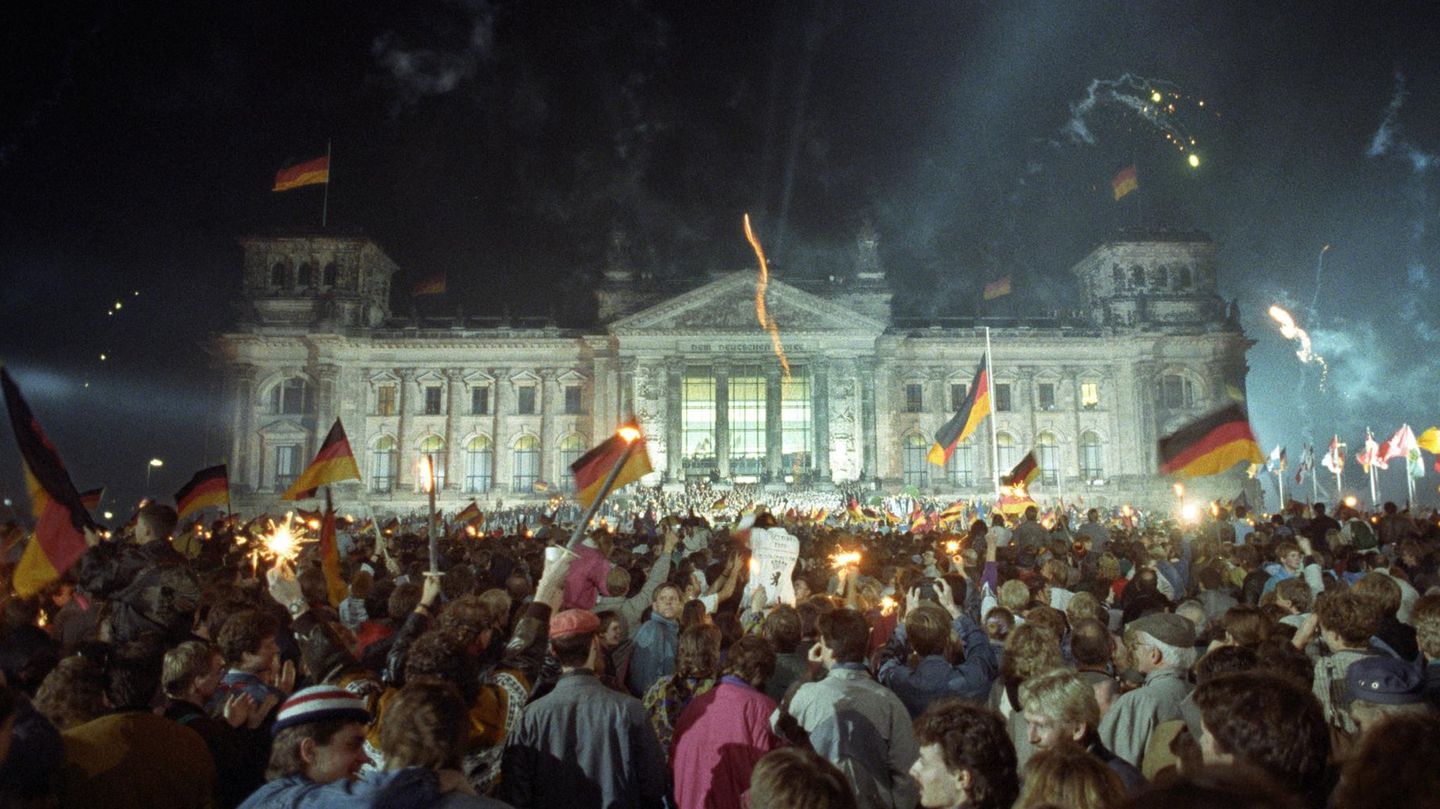 Mit Feuerwerk und Deutschlandfahnen feiern Tausende Menschen vor dem Reichstagsgebäude in der Nacht