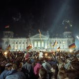 Mit Feuerwerk und Deutschlandfahnen feiern Tausende Menschen vor dem Reichstagsgebäude in der Nacht