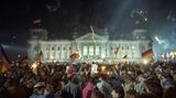 Mit Feuerwerk und Deutschlandfahnen feiern Tausende Menschen vor dem Reichstagsgebäude in der Nacht