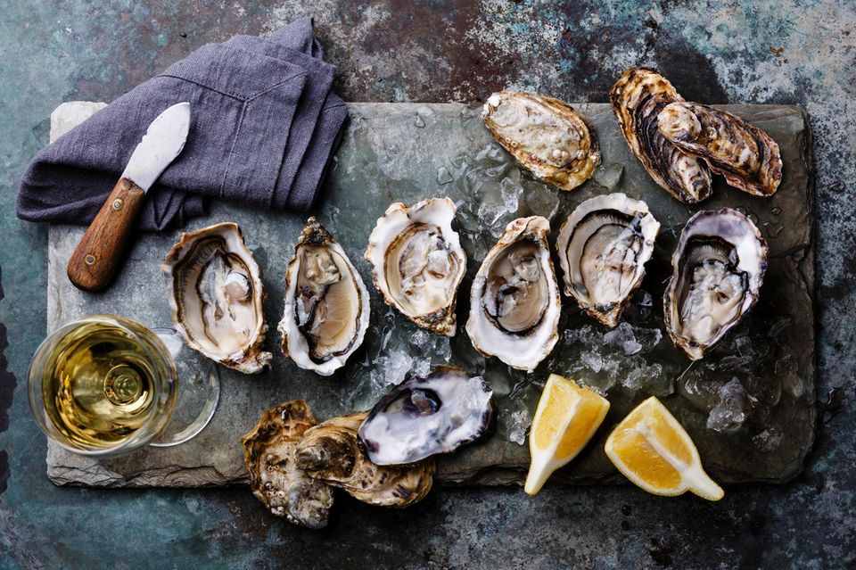 Muscheln essen: geöffnete Austern auf Eis mit Zitronenscheiben