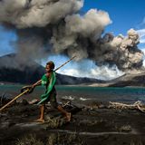 Ein Junge spielt vor einem ausbrechenden Vulkan im Hintergrund