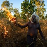 Ein Aborigine in West Arnhem Land legt Feuer, und das mit voller Absicht: