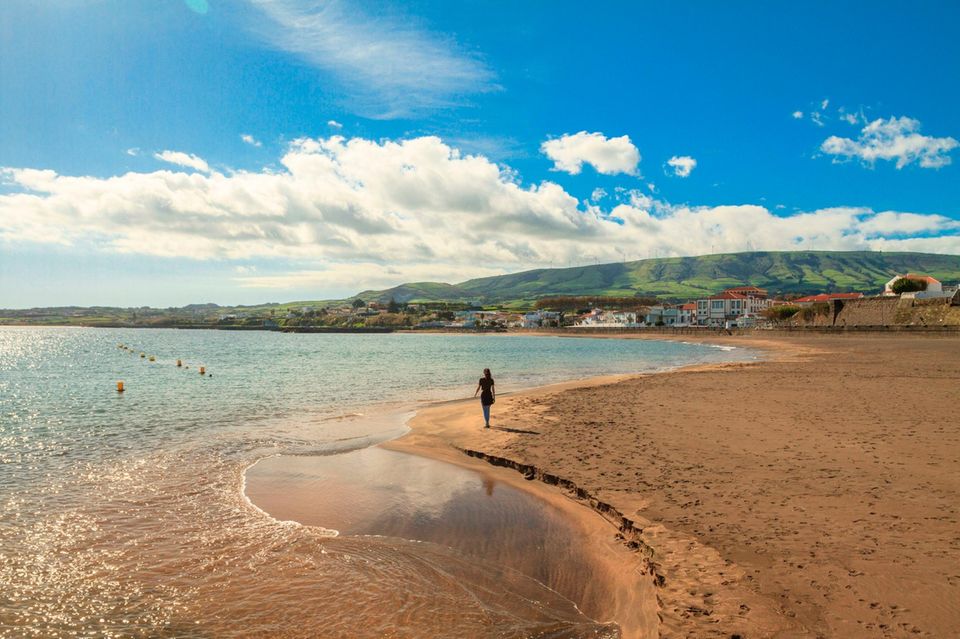 Junge Frau läuft am einsamen Praia Grande in der Praia de Vitoria entlang