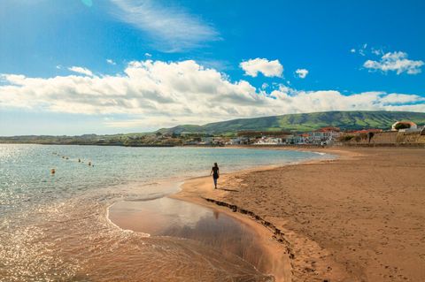 Junge Frau läuft am einsamen Praia Grande in der Praia de Vitoria entlang