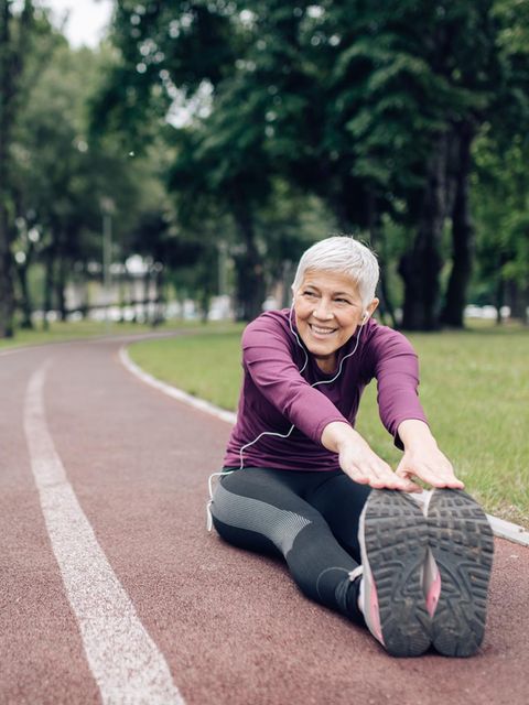 Ältere Frau in Sportkleidung beim Stretching auf einem Sportplatz
