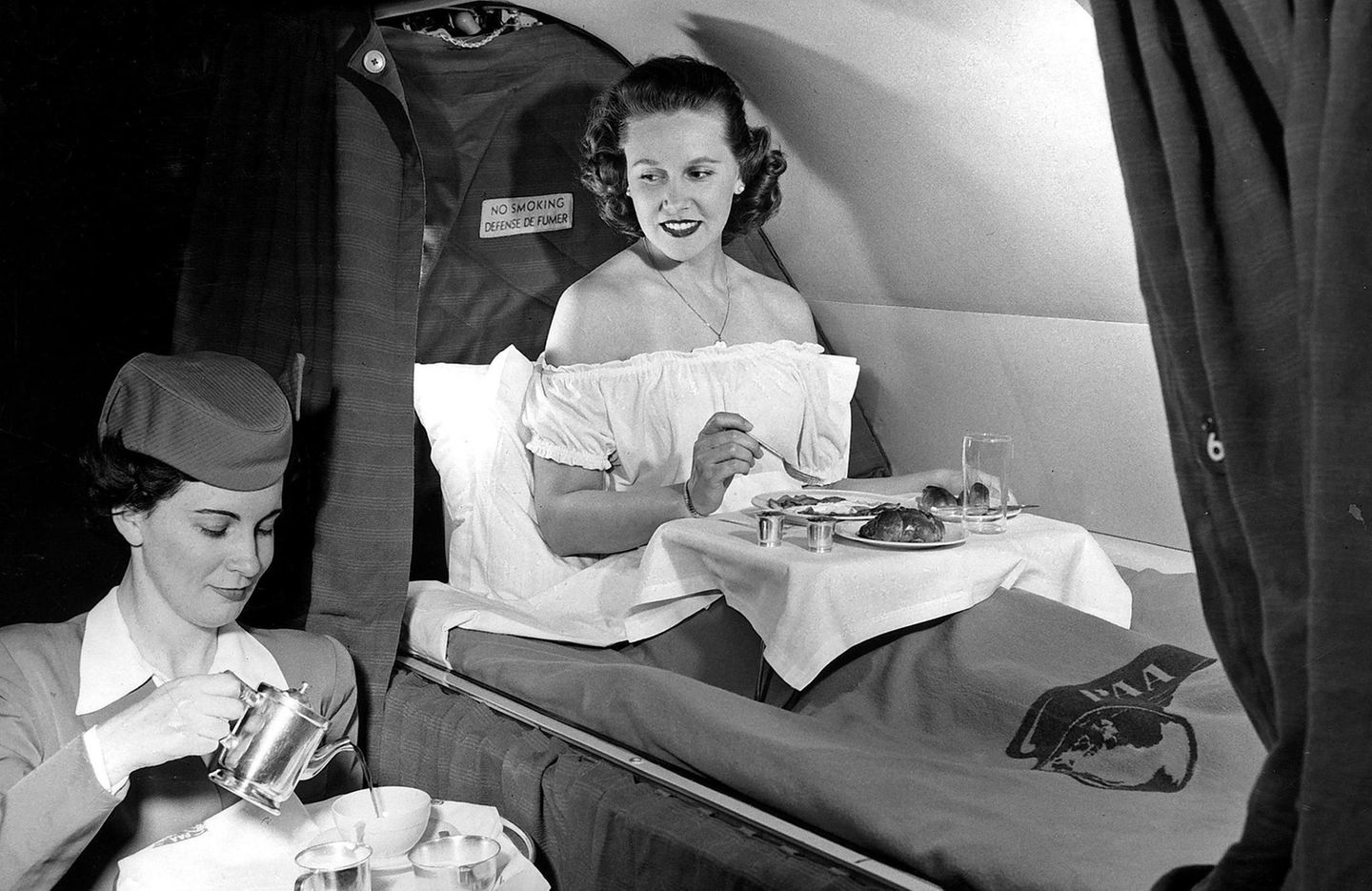 Eine Stewardess serviert auf einem Pan-Am-Transatlantikflug 1952 das Frühstück. Der Komfort lässt in Maschinen wie der Boeing 377 Stratocruiser wenig zu wünschen übrig: Dort lassen sich Sitze in Betten verwandeln und gibt es Waschräume für die betuchte Kundschaft, um sich für den perfekten Auftritt am Zielort vorzubereiten