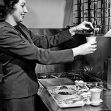 Eine Stewardess der Trans World Airlines richtet einen Imbiss an (1954). Die Passagiere der Interkontinentalflüge sind anspruchsvoll, kostet doch etwa ein Flug von Deutschland nach New York in jenen Jahren ungefähr so viel wie ein VW Käfer. Entsprechend umgarnen Fluglinien ihre reiche Klientel mit gehobener Ausstattung und hervorragendem Service