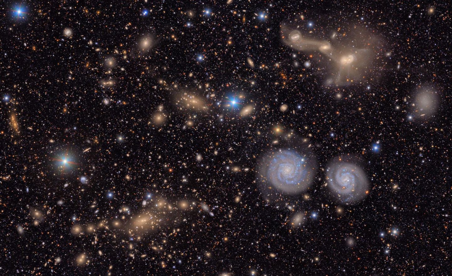 Eines der ersten Bilder, die das Team des gerade in Betrieb genommenen Vera C. Rubin Observatory der Öffentlichkeit präsentierte. Es zeigt einen Ausschnitt des Virgo-Galaxiehaufens, der bis zu 2000 Galaxien umfasst. Sterne in der Milchstraße funkeln blau, nahe Spiralgalaxien erscheinen weiß. Weit entfernte, elliptische Galaxien leuchten gelb und orange. Anhand der Farben des Lichts können Forschende ihre Entfernung bestimmen. Tatsächlich sehen wir nur einen kleinen Ausschnitt der eigentlichen Aufnahme. Das Bild, das die Kamera des Observatoriums auf ihren Sensor bannt, ist 50-mal größer. Um alle Feinheiten mit bloßem Auge betrachten zu können, bräuchte es einen hochauflösenden Bildschirm von der Größe eines Basketballfelds. Nur so ließen sich Details wie die verschmelzenden Galaxienpaare oben rechts im Bild erkennen.