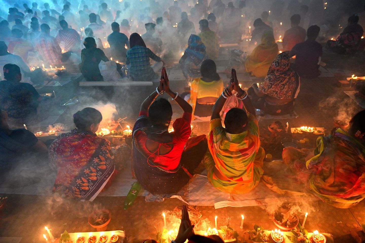 Nach Sonnenuntergang haben sich die Anhänger des spirituellen Meisters Lokenath Brahmachari in einem Ashram versammelt und Kerzen entzündet. Nun brechen sie gemeinsam das Fasten, bringen Früchte und Blumen dar und rezitieren Gebete und Mantras. Der Monat Kartik gilt in der hinduistischen Gemeinschaft Bangladeschs als besonders heilig.