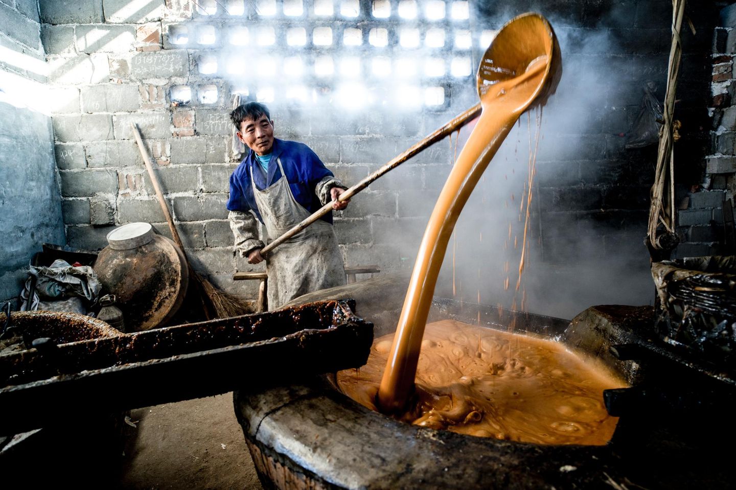 Die Bauern im Süden Chinas haben ihre ganz eigene traditionelle Methode, um Zucker zu gewinnen. Dazu pressen sie ihr geerntetes Zuckerrohr aus und kochen den gewonnenen Saft mehrmals auf, so wie dieser Bauer aus der Provinz Jiangxi es tut. Wenn alles Wasser verkocht ist, bleibt brauner Zucker übrig, der für die Herstellung von Sirup und süßem Gebäck verwendet wird.