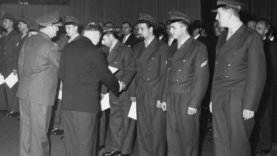 1955 ernennt der damalige Verteidigungsminister Theodor Blank die ersten 100 Freiwilligen zu Bundeswehrsoldaten. Die Männer tragen zivile Anzüge, weil ihre Uniformen noch nicht fertig genäht sind