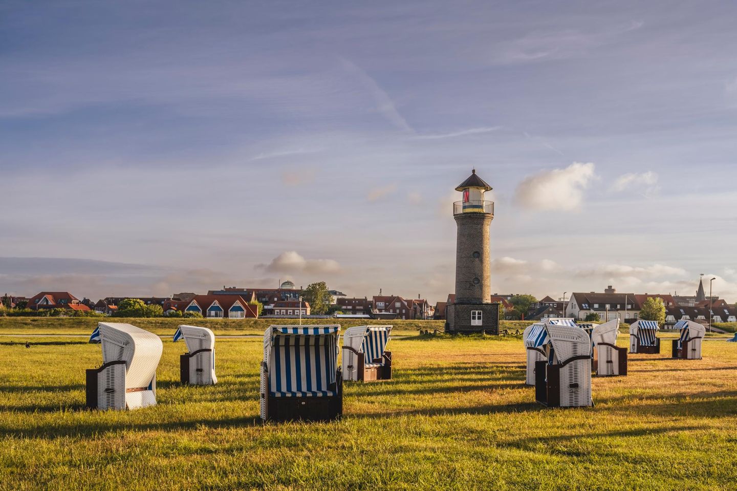 Germany, Lower Saxony, Juist, Hooded beach chairs in front of Memmertfeuer lighthouse