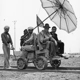 Vier Männer sitzen auf Schienen-Wagen