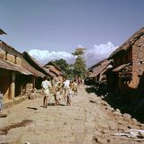 Menschen laufen in einem Dorf über eine gepflasterte Straße