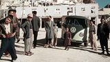 VW Bulli umringt von Menschen vor Hochgebirge