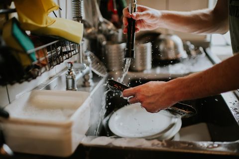 Ein Mann wäscht Geschirr mit der Hand  ab
