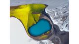Im südlichen Hochland Islands taucht der Herbst die Natur in Farben, so kräftig wie aus dem Malkasten: Das satte Blau eines Kratersees kontrastiert mit dem leuchtenden Grün moosbewachsener Berghänge und dem schlammigen Grau des Flusses Skaftá, der sich aus einem Gletscherlauf speist. Die Aufnahme von Andro Loria gehört zu den 100 besten Fotografien des "International Aerial Photographer of the Year".