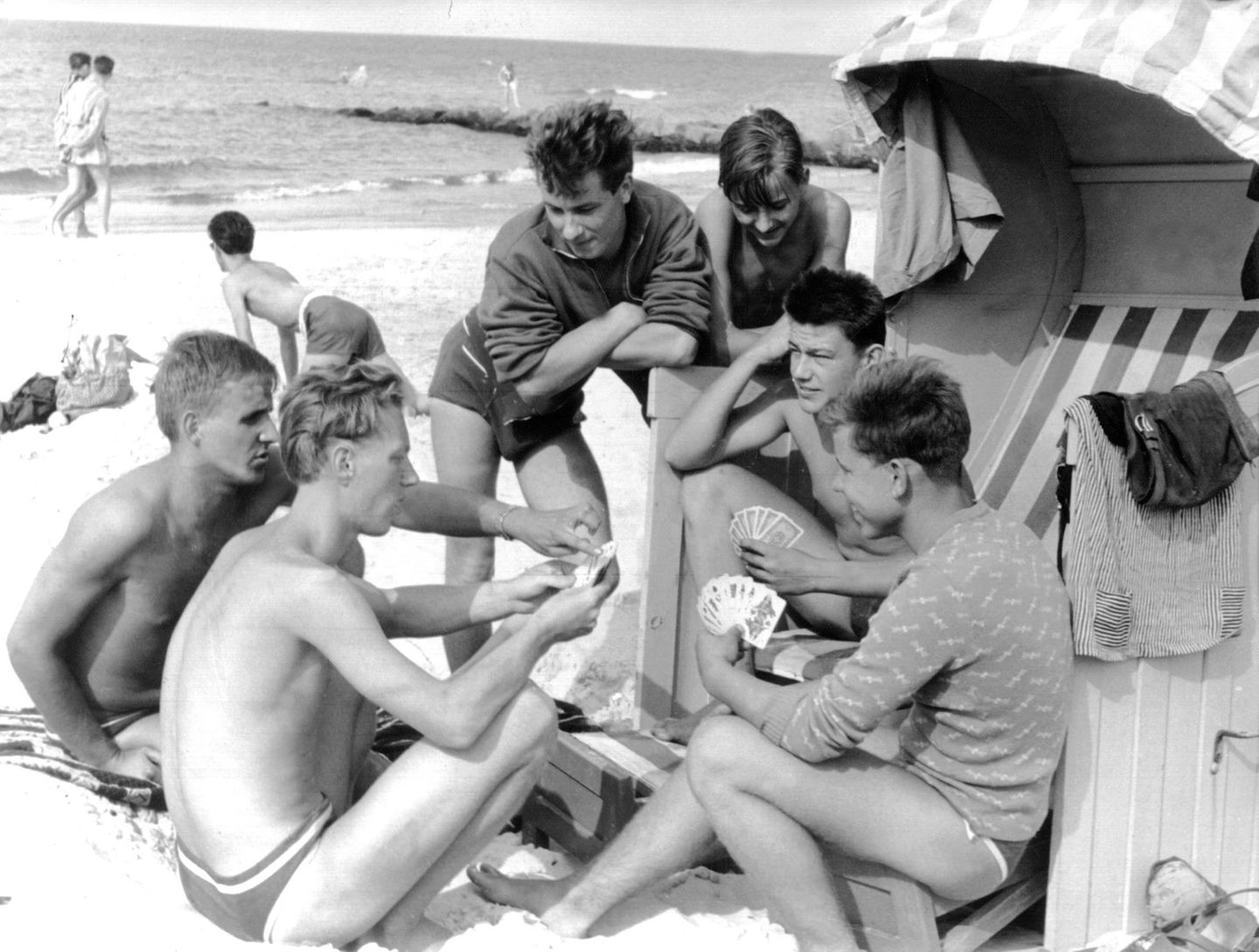 Beschaulich ist sie, die Ostsee – für die Jugend damals wie heute vielleicht sogar ein wenig zu sehr. Eine Runde junger Männer vertreibt sich die Zeit mit Skat am Strand von Zingst. Aufgenommen am 15. August 1960.