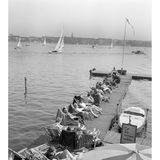 Sonnige Stunden an der Außenalster: Am 24. April 1962 genießen zahlreiche Hamburger das warme Frühlingswetter. Die Terrassen der Cafés sind belebt, Liegestühle am Wasser begehrt – kaum ein Platz bleibt frei. Wer will, kann aufs Wasser: Eine oder zwei Personen zahlen drei D-Mark für eine Stunde Tretbootvergnügen.