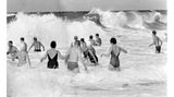 Wenningstedt, 1965 Unverzagt genießen Badegäste den starken Wellengang und die erfrischende Gischt am Strand in Wenningstedt auf der Nordseeinsel Sylt.
