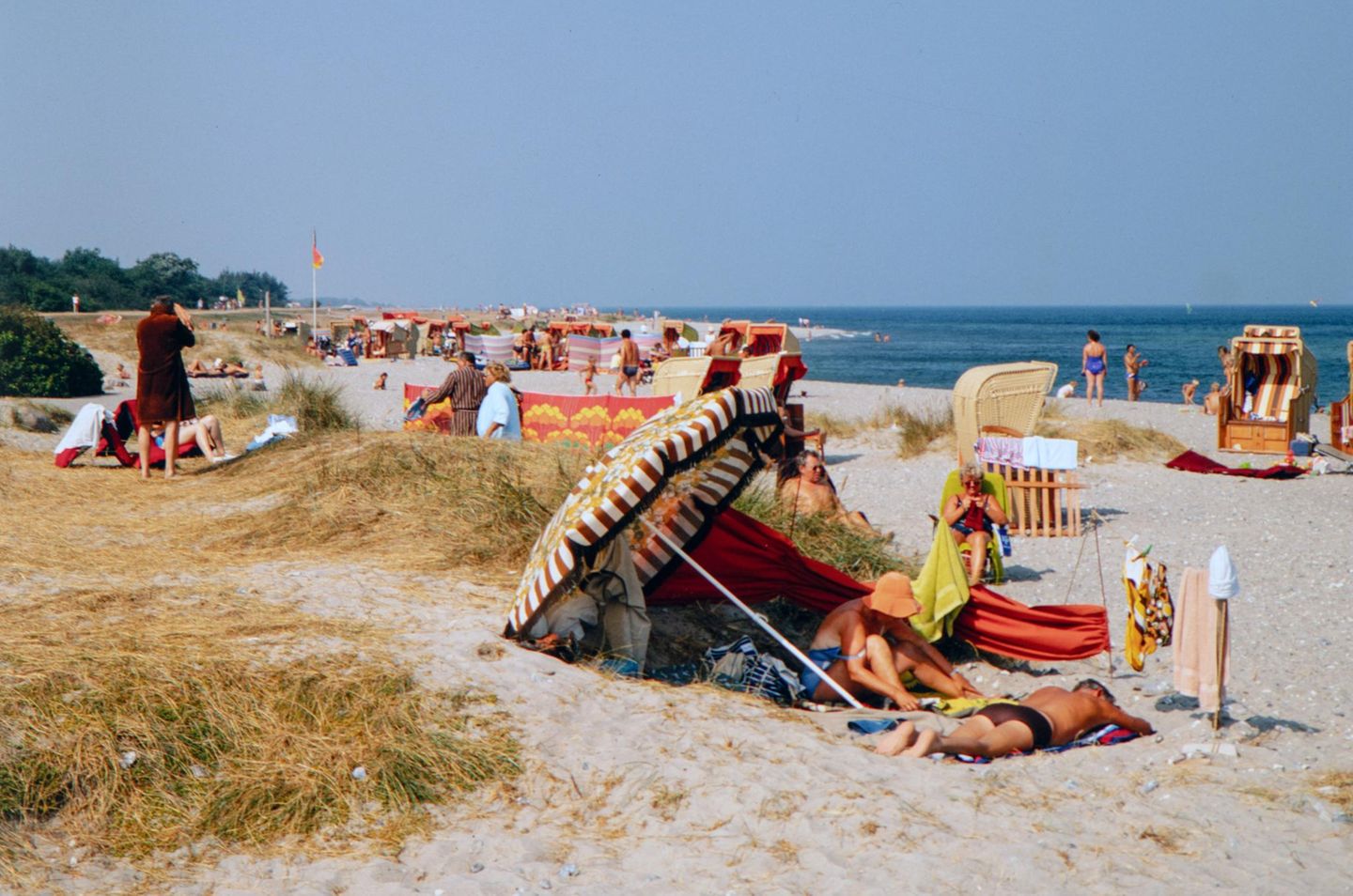 Die einen stricken, die anderen lesen oder genießen einfach die Sonne: Bei sommerlichen Temperaturen zieht es Badegäste an den weiten Strand der beliebten Ferieninsel Fehmarn.