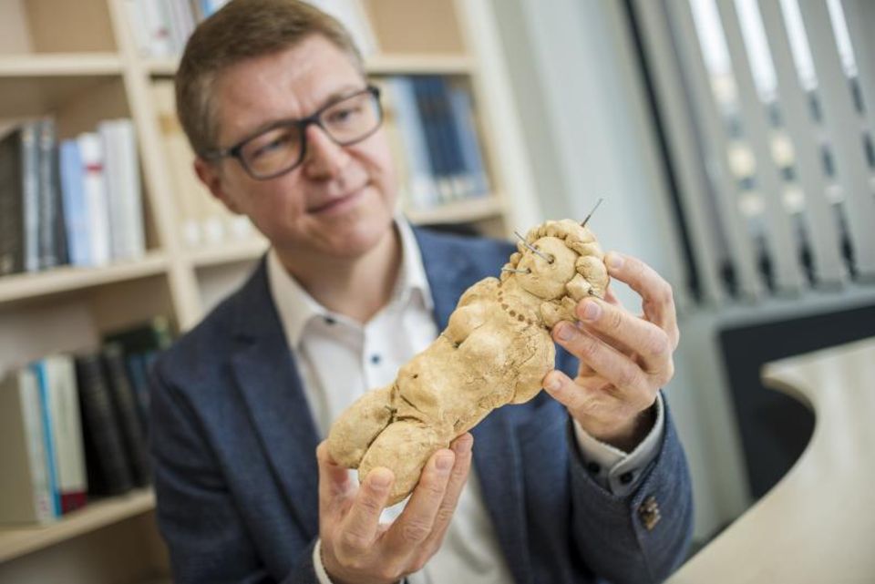 Michael Hölscher hält Puppe aus Lehm in der Hand