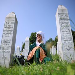 Eine muslimische Frau trauert zwischen Grabsteinen um die Opfer des Massakers von Srebenica