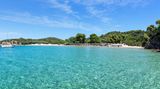Panoramablick auf Tsoungria, im Vordergrund das Meer, im Hintergrund Strand und Bäume
