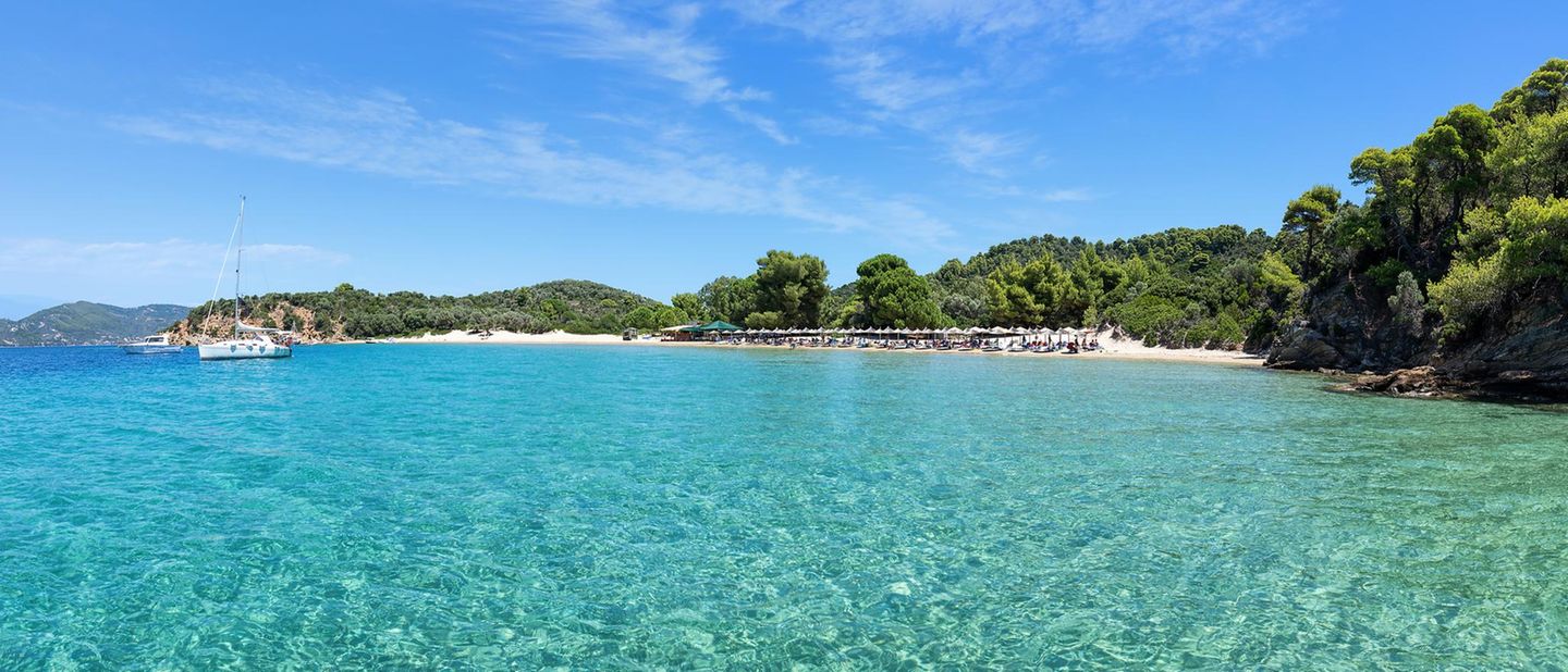 Panoramablick auf Tsoungria, im Vordergrund das Meer, im Hintergrund Strand und Bäume