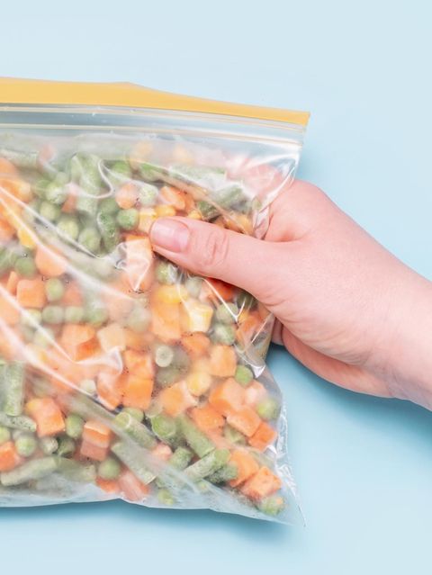 Eine Hand hält einen Beutel mit tiefgekühltem Gemüse