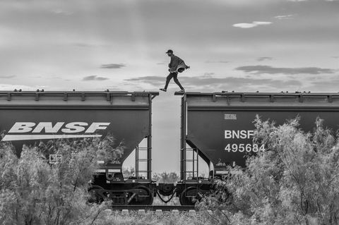 Person läuft von Wagon zu Wagon auf den Dächern eines Zuges.
