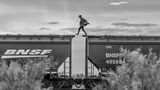 Person läuft von Wagon zu Wagon auf den Dächern eines Zuges.