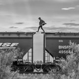 Person läuft von Wagon zu Wagon auf den Dächern eines Zuges.