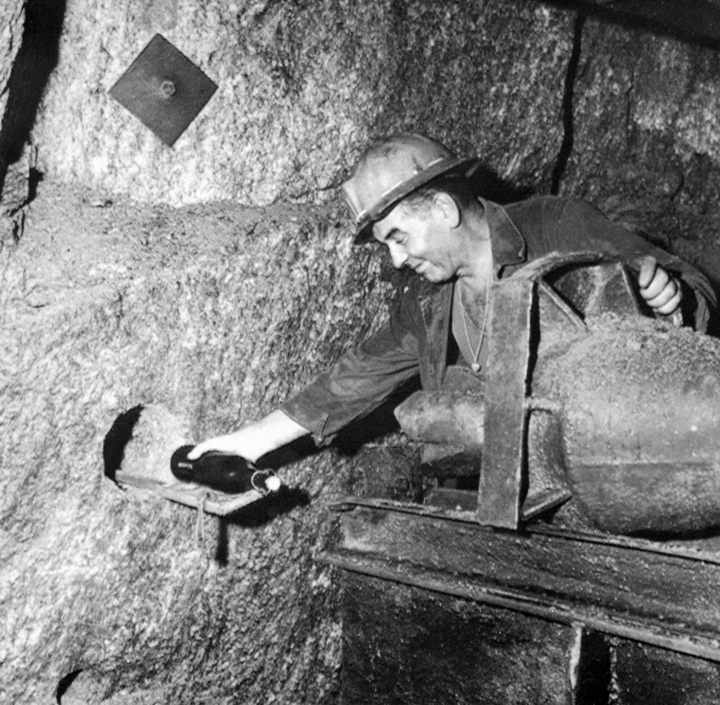Rendezvous im Stollen Ein Bergwerksleiter nimmt durch ein Loch in einer Steinwand eine Flasche entgegen