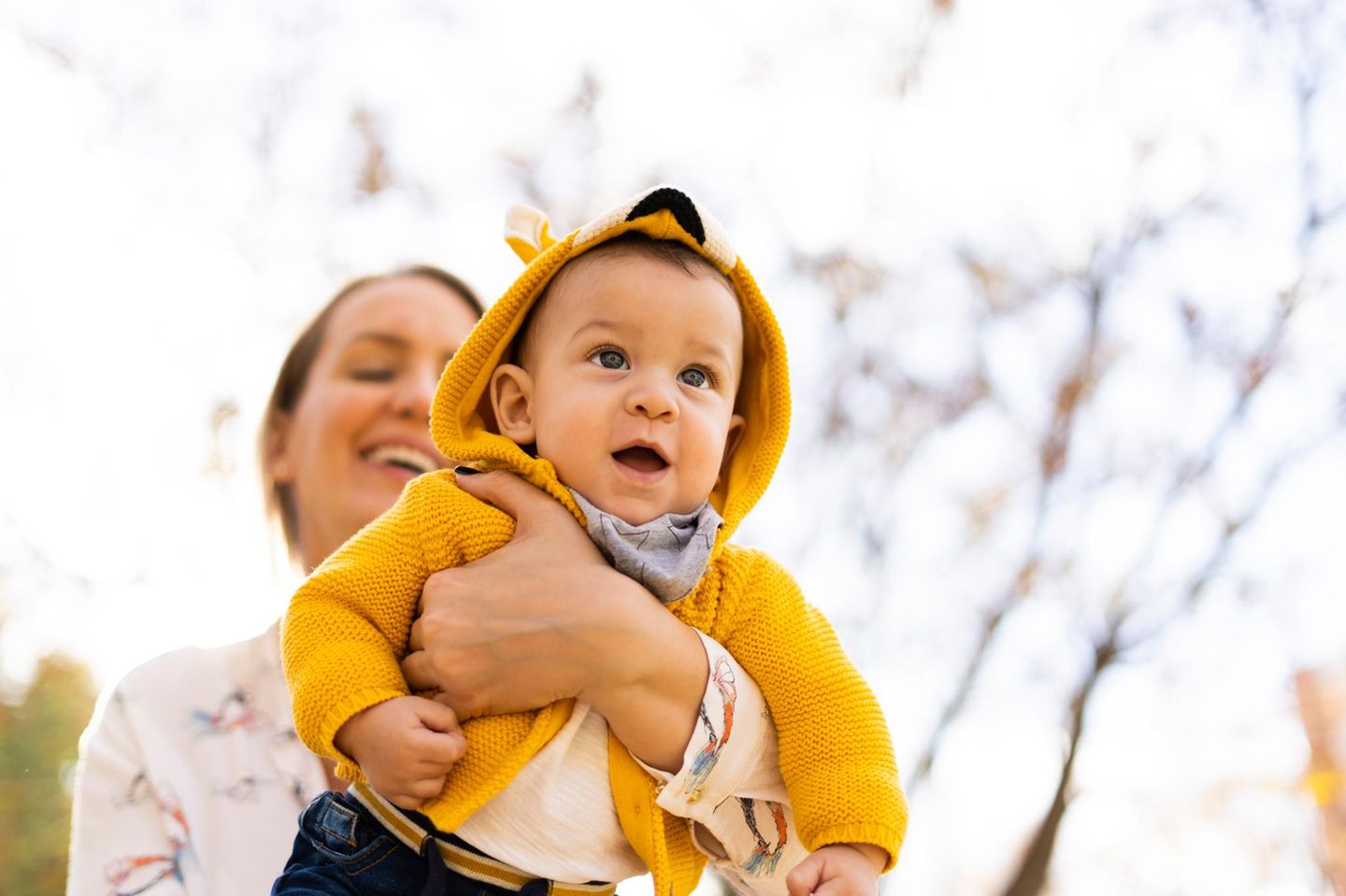 Happy mother carrying baby boy in a park