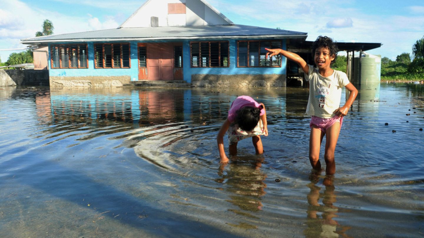 Kinder spielen auf einem vom Meerwasser überflutetem Platz in Funafuti, der Hauptstadt von Tuvalu. Australien will vom Klimawandel betroffene Menschen aus dem Südseestaat Tuvalu aufnehmen und ihnen ein dauerhaftes Aufenthaltsrecht gewähren