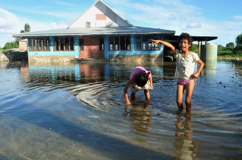 Kinder spielen auf einem vom Meerwasser überflutetem Platz in Funafuti, der Hauptstadt von Tuvalu. Australien will vom Klimawandel betroffene Menschen aus dem Südseestaat Tuvalu aufnehmen und ihnen ein dauerhaftes Aufenthaltsrecht gewähren